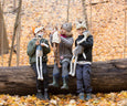 3 children playing in the woods wearing fox, bunny and cat animal headdresses and holding racoon, fawn and badger cloth dolls.